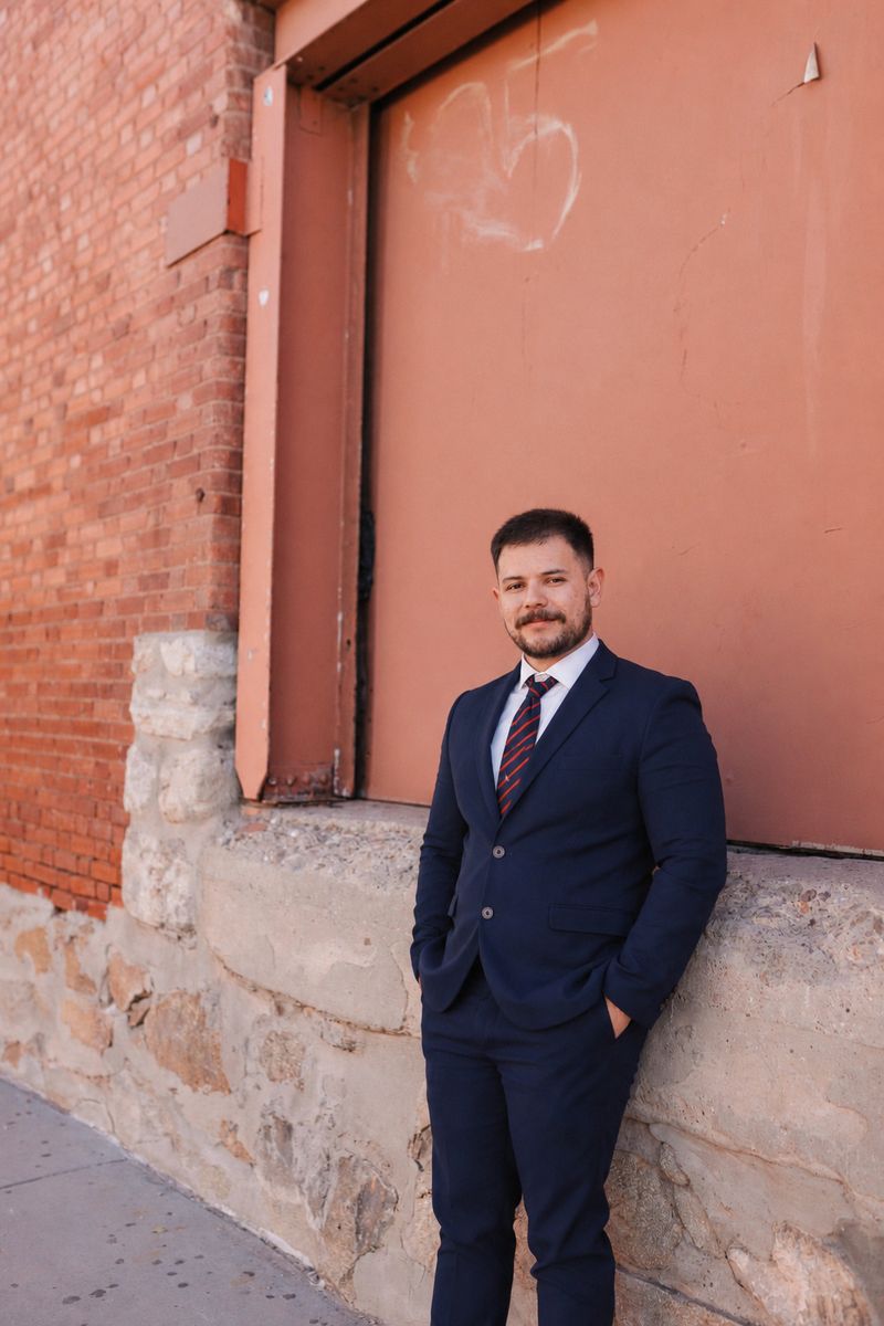 Oscar, owner of BlackBeard Web Design, in a navy suit beside a brick building in El Paso